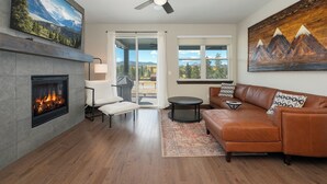 Ein modernes Wohnzimmer mit Kamin, Ledersofa und großem Fenster mit Blick auf die Berge.