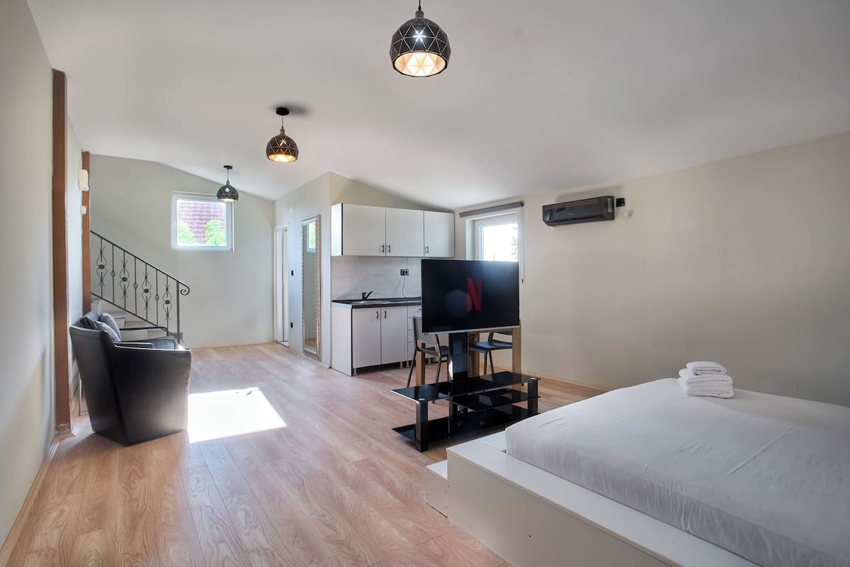 Een moderne kamer met een bed, een televisie, een bureau en een keukenhoek.