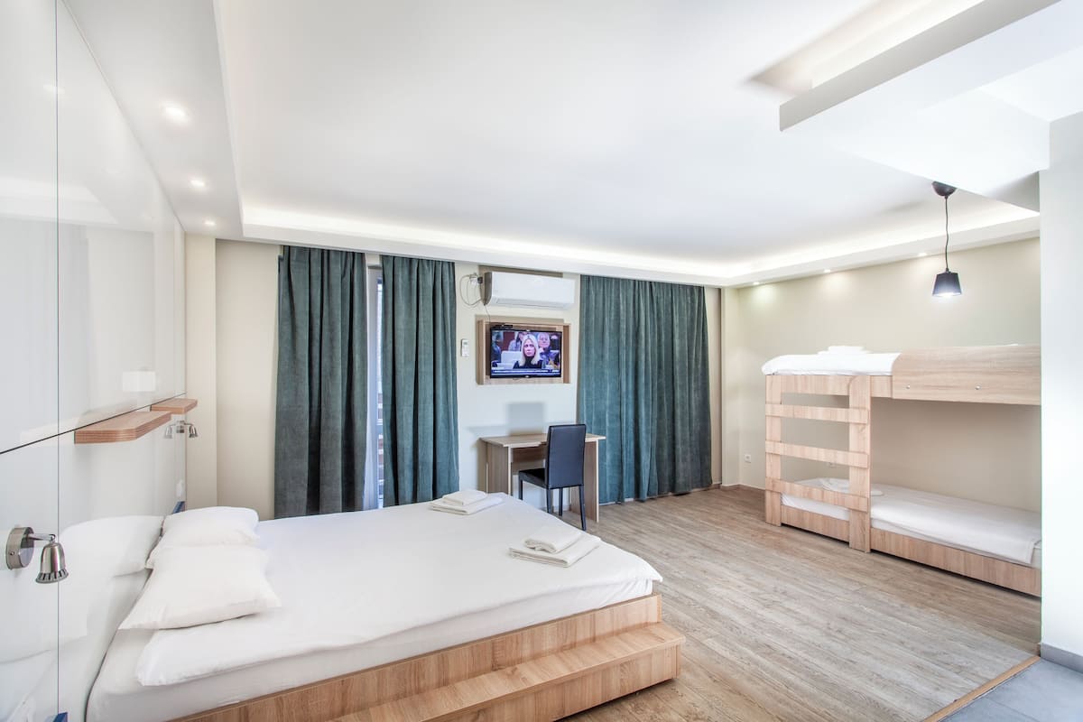 Een moderne hotelkamer met een groot bed, een bureau en een stapelbed.