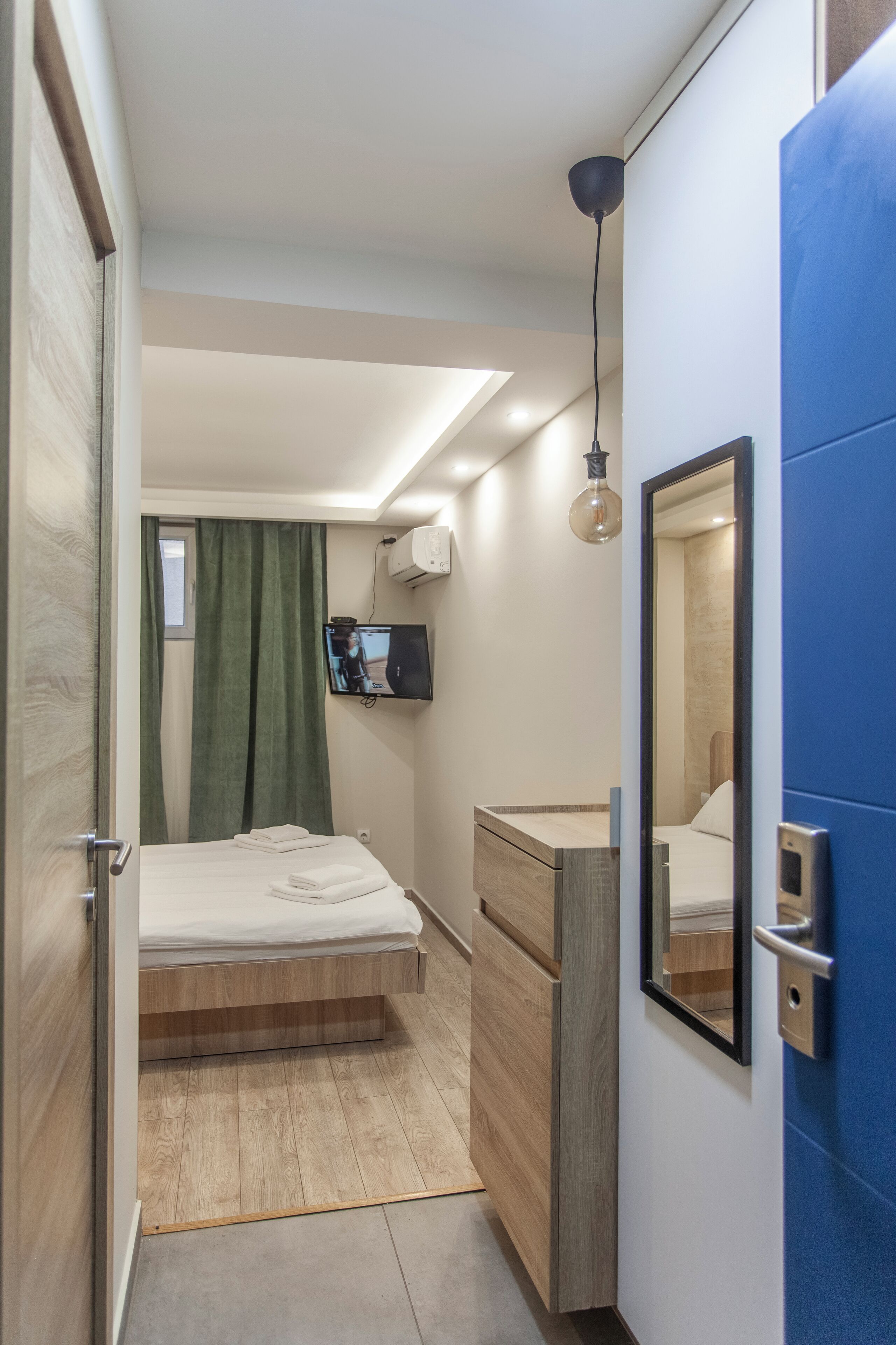 Quarto moderno com cama, penteadeira, espelho, televisão e luminária de teto.