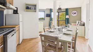 Une cuisine moderne avec un coin repas, un plancher en bois et une vue sur l’extérieur.