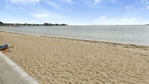 Une plage de sable fin, avec un ciel dégagé et une mer calme.