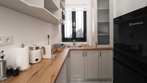 Une cuisine moderne avec des meubles blancs, un réfrigérateur noir et des plans de travail en bois.