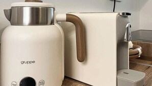 Une cuisine moderne avec un appareil électroménager blanc, un manche en bois et un panneau de commande doté de boutons indiquant « TEMP » et « ARRÊT ÉBULLITION ».