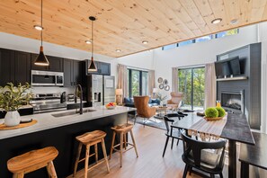 A modern kitchen with dark cabinets, stainless steel appliances, and a wooden ceiling. - Sevierville Retreat • Indoor Pool + Hot Tub + Firepit + Gym | Ridgeview Retreat (Sevierville)