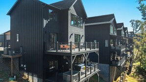 A modern multi-story house with a balcony, outdoor seating, and a hot tub. - Sevierville Retreat • Indoor Pool + Hot Tub + Firepit + Gym | Ridgeview Retreat (Sevierville)