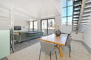 A modern interior with a dining area, sofa, and staircase.