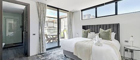 A modern bedroom with a large bed, a glass door leading to a balcony, and a city view.