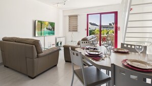 A modern living room with a sofa, dining table set for two, and a painting on the wall. - House in residence, pool, 2 adults/2 children (Le Croisic)