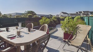 A patio with a table set for dining, surrounded by chairs and potted plants. - House in residence, pool, 2 adults/2 children (Le Croisic)