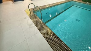 An indoor swimming pool with a tiled floor, a poolside seating area, and a ceiling with recessed lighting. - Khorazm Hotel (Tashkent)