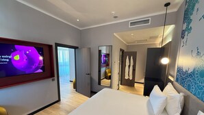 A modern hotel room with a large bed, a flat-screen TV, a mirror, and a view of the hallway. - Khorazm Hotel (Tashkent)