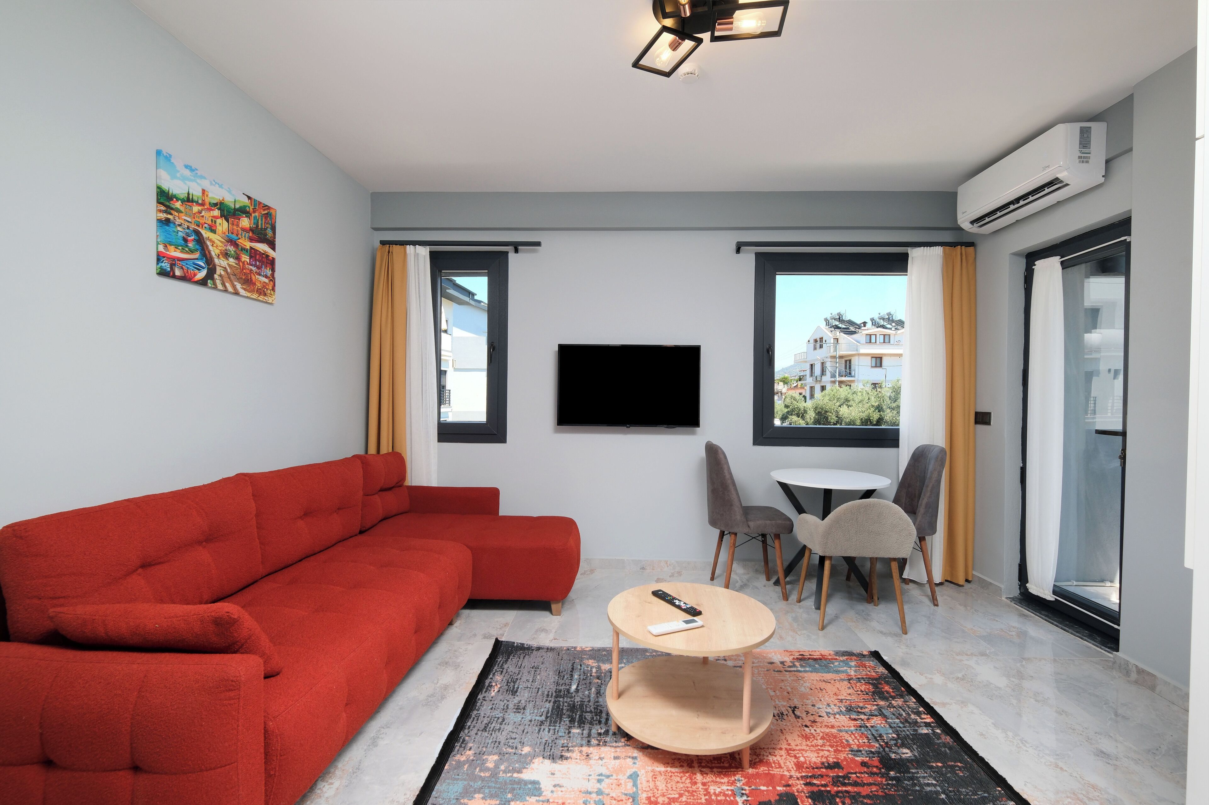 A modern living room with a red sofa, a round coffee table, and a flat-screen TV.