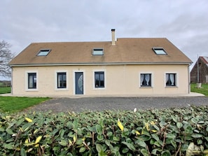 A two-story house with a sloped roof, multiple windows, and a chimney.