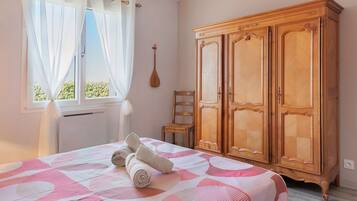 Un dormitorio con una cama, un armario de madera, una silla y una ventana con cortinas.