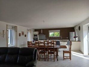 Une cuisine moderne avec un coin repas, un canapé en cuir noir et une fenêtre donnant sur un paysage verdoyant.