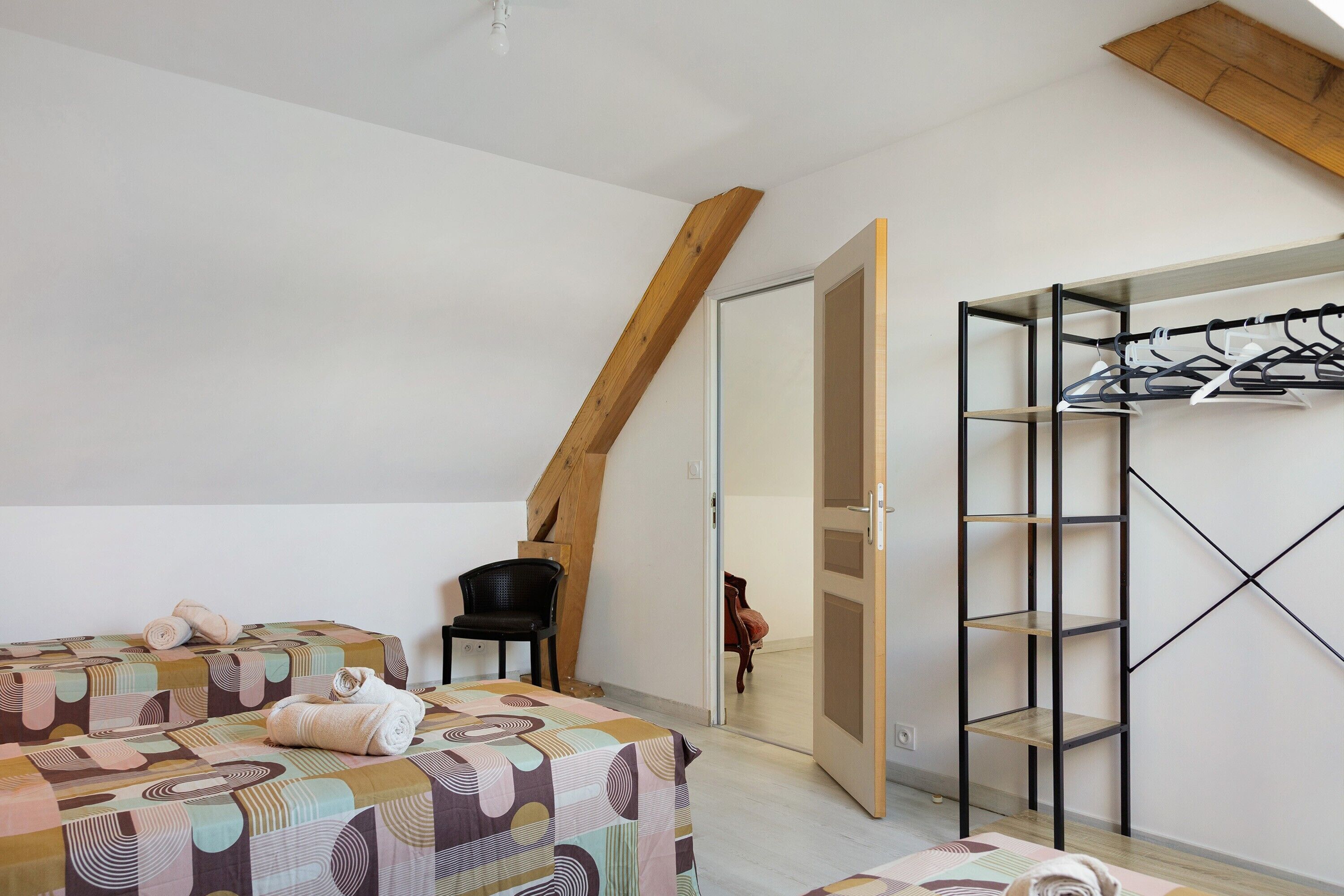 Ein Schlafzimmer mit einem Bett, einem Sessel, einem Kleiderschrank und einem Holzbalken an der Decke.