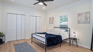 A bedroom with a bed, a ceiling fan, a window with blinds, and a door. - Ultimate 4 Bedroom Comfort So Close to Riverwalk! (San Antonio)