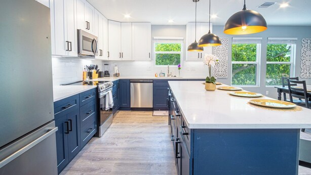 A modern kitchen with white cabinets, a large island, stainless steel appliances, and pendant lighting. - Pleasant & Relaxing 5BR/2.5BA Home Near Riverwalk (San Antonio)