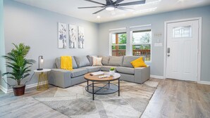 A modern living room with a sectional sofa, a round coffee table, and a ceiling fan. - Pleasant & Relaxing 5BR/2.5BA Home Near Riverwalk (San Antonio)