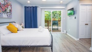 A bedroom with a bed, a ceiling fan, a TV mounted on the wall, and a sliding glass door leading to an outdoor area. - Pleasant & Relaxing 5BR/2.5BA Home Near Riverwalk (San Antonio)