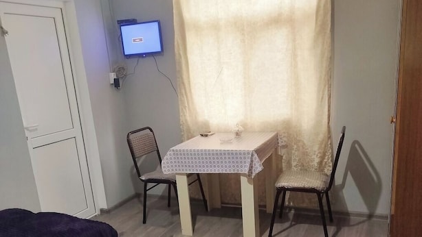 A room with two beds, a small table with chairs, a TV, and an air conditioning unit. - Sabir iki (Baku)