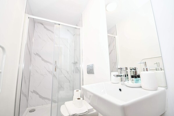 A modern bathroom with a marble shower enclosure, a white sink with chrome fixtures, and a large mirror. - Modern & Bright 1BED Flat in Central Sheffield (Sheffield)