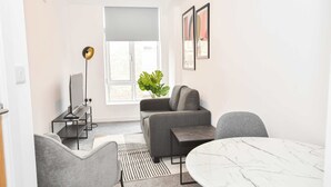 Moderni olohuone, jossa on sohva, sohvapöytä, lattiavalaisin ja ruukkukasvi.