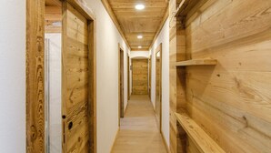 A wooden interior hallway with a ceiling light, wooden walls, and a door at the end.