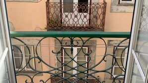 A balcony with ornate metal railings and a view of a building with three windows. - Portuguese Classic Flat at Lisbon Historic Center (Lisboa)