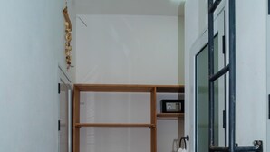 A hallway with a wooden closet, a white towel hanging, and a door with a black frame. - Cattleya Guest House (Nosy Be)