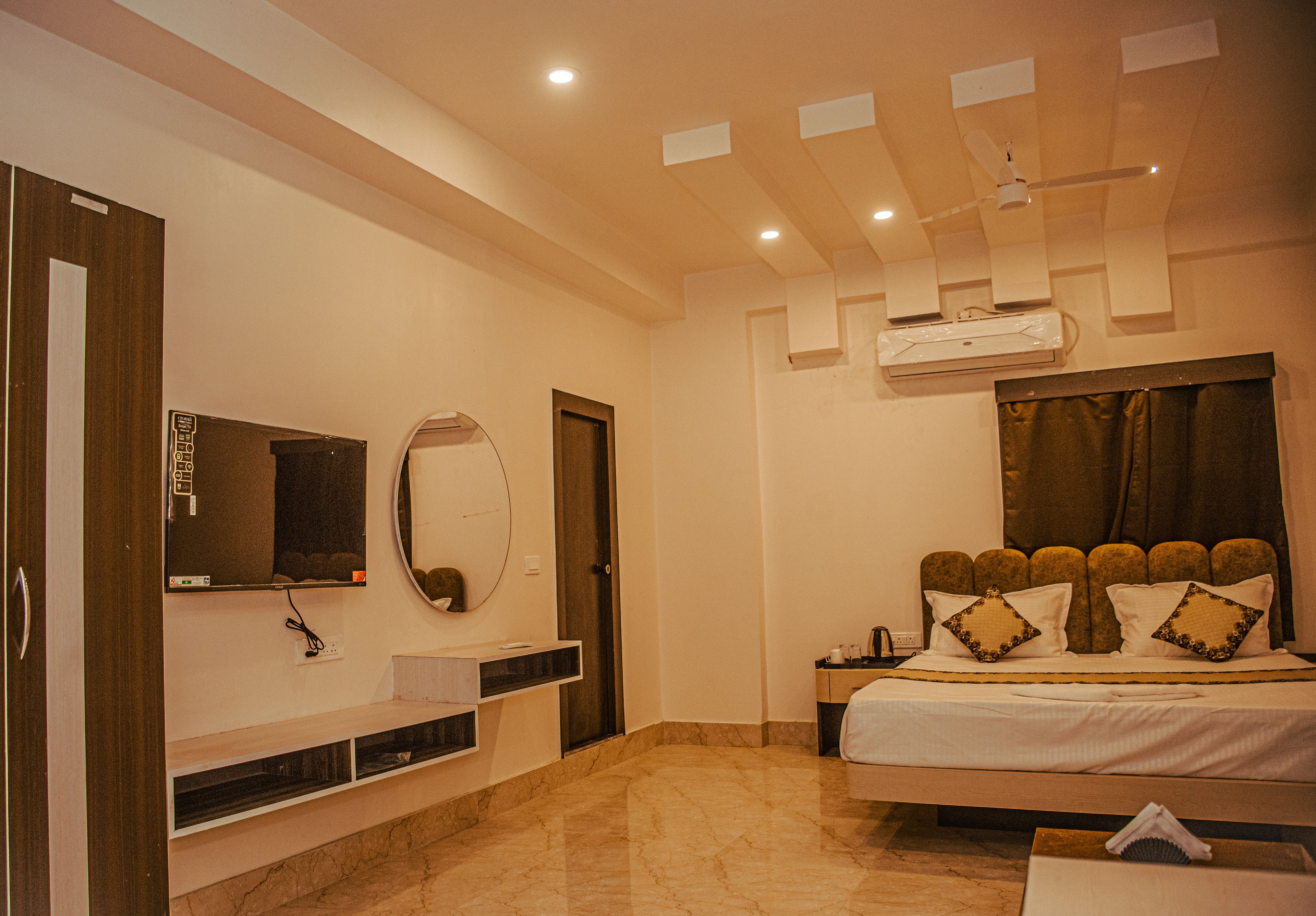 Una habitación ejecutiva bien iluminada con cama, televisión, espejo y armario.