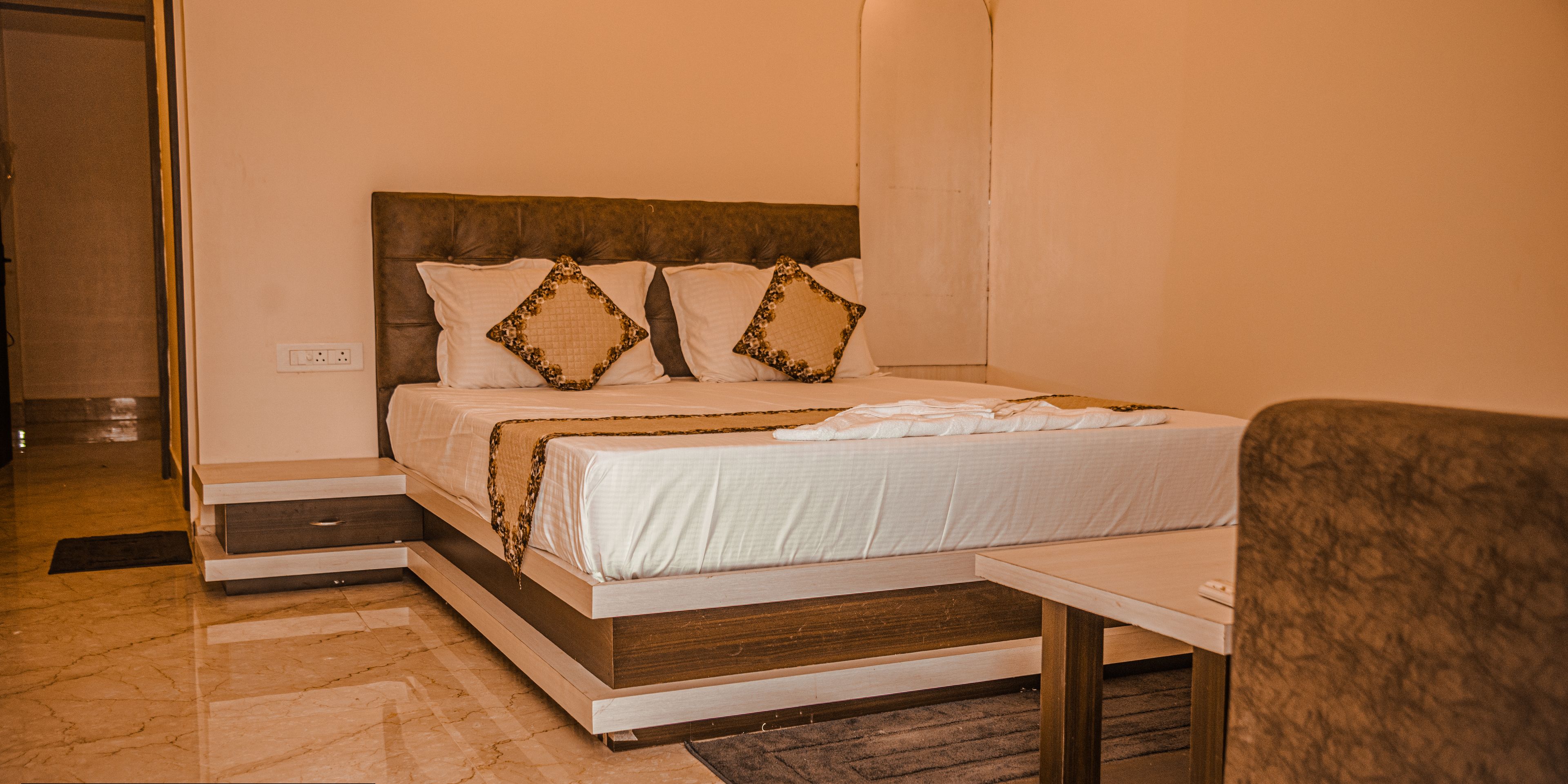 A hotel room with a bed, bedside table, and a chair.
