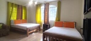Una habitación con dos camas, una mesita y una ventana con cortinas.