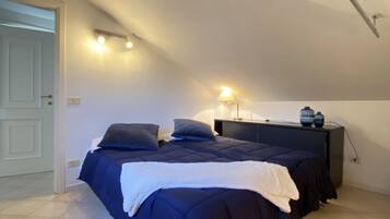 Un dormitorio con cama, mesita de noche, lámpara y dos jarrones.
