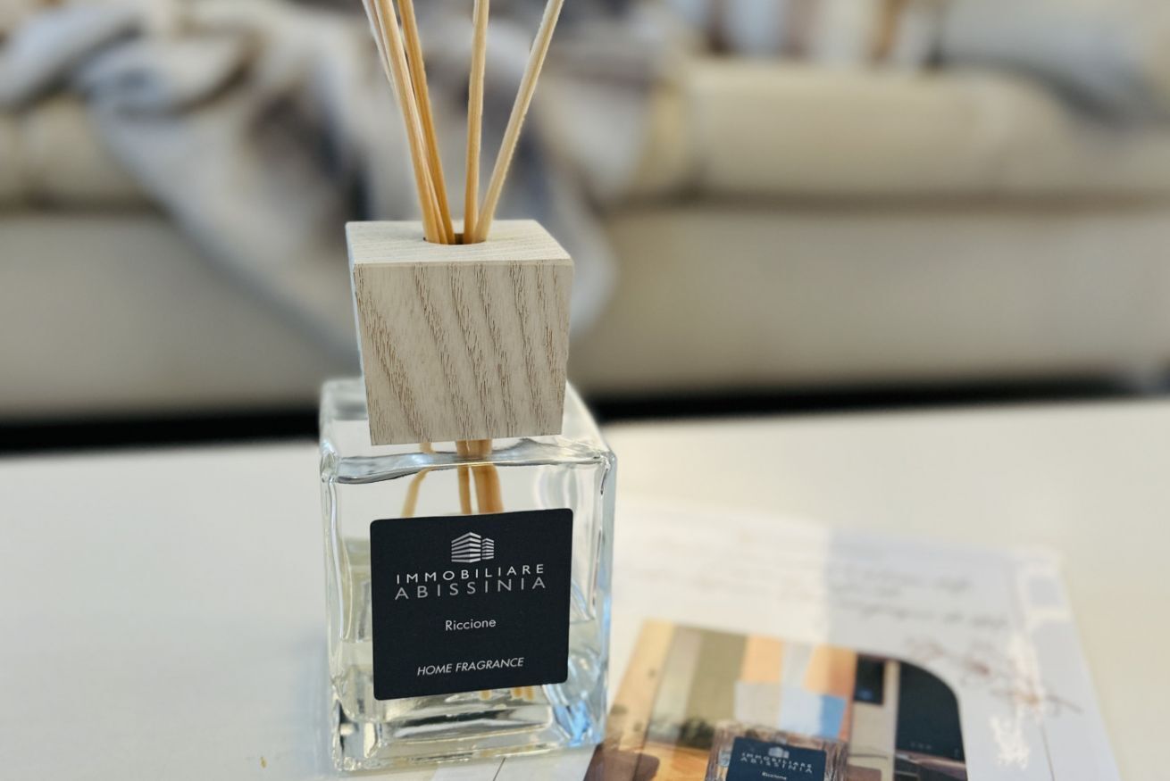 A bottle of 'IMMOBILIARE ABISSINIA' home fragrance with reed sticks.