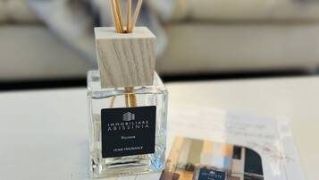 A bottle of 'IMMOBILIARE ABISSINIA' home fragrance with reed sticks.
