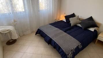 A bedroom with a bed, a nightstand, a lamp, and a window with curtains.