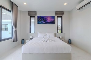A modern hotel room with a large bed, a painting above the bed, and a view through the window. - 2 Villas 2 Kitchens  Huge Pool V258 (Rawai)