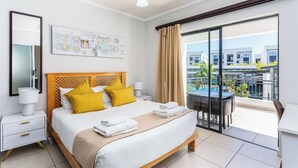 Une chambre d’hôtel moderne dotée d’un grand lit, d’un balcon avec vue sur la piscine et d’un coin repas.