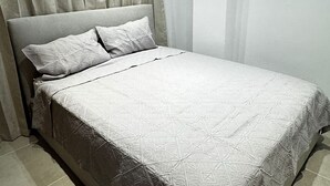 Una cama bien hecha con una colcha de estampado geométrico y dos almohadas.