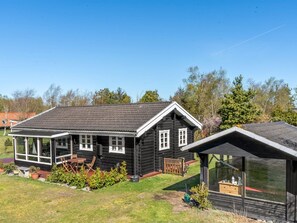 A log cabin with a porch, a small attached structure, and a well-maintained garden.