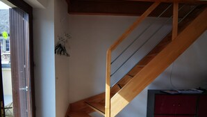 Una escalera con escalones de madera y barandillas de metal, un armario rojo y una puerta que da al exterior.