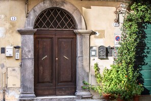 A double wooden door with a metal grille, flanked by stone columns, and a green wall with a no parking sign. - Casa Sophia, a timeless stay in Lucca (Lucca)