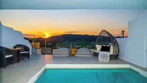 Une terrasse sur le toit avec une piscine, des espaces de détente et une vue sur le coucher de soleil sur les montagnes.