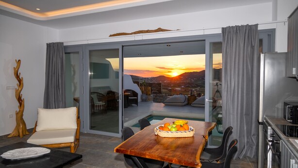 Un salon moderne comprenant un coin repas, une porte vitrée donnant sur un balcon avec vue sur la ville et un espace cuisine.