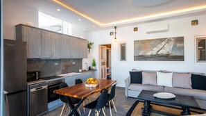 A modern kitchen with a dining area, a sofa, and a painting on the wall.