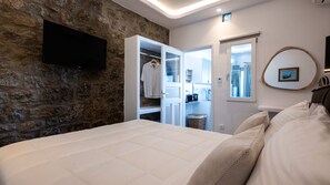 Een slaapkamer met een stenen muur, een bed, een kledingkast en een televisie.