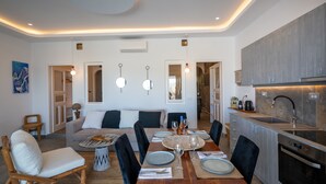 A modern kitchen with a built-in oven, a dining area with a round table and chairs, and a living room with a sofa and a coffee table. - Premium 2 Bedroom House with Private Pool (Mykonos)
