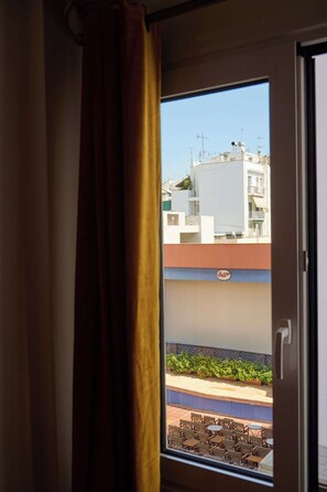 Une fenêtre donnant sur un immeuble doté de balcons et sur lequel on peut lire l’inscription « Azzurri ».